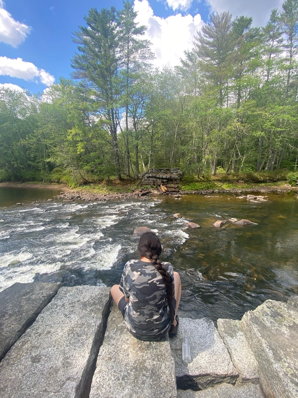 Water rapids in 2022 at the canoeing trip, with a girl sitting on a rock